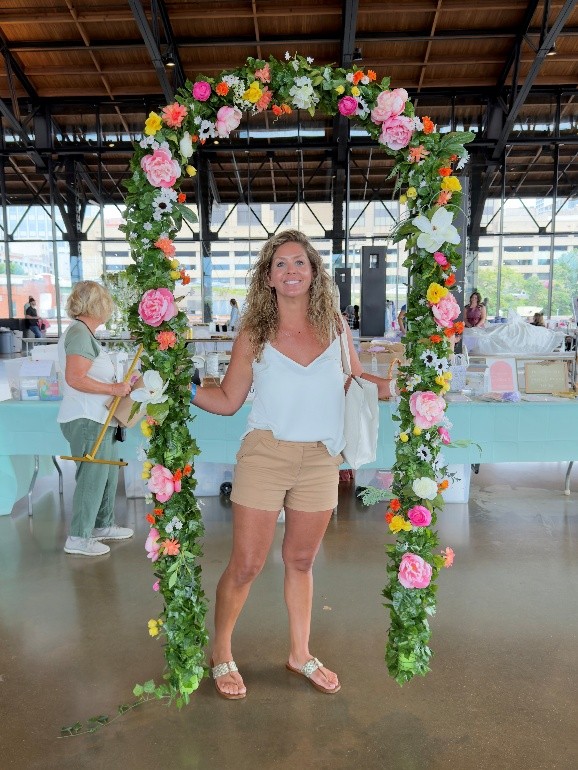 A woman standing under a floral archway at The Wedding Yard Sale
