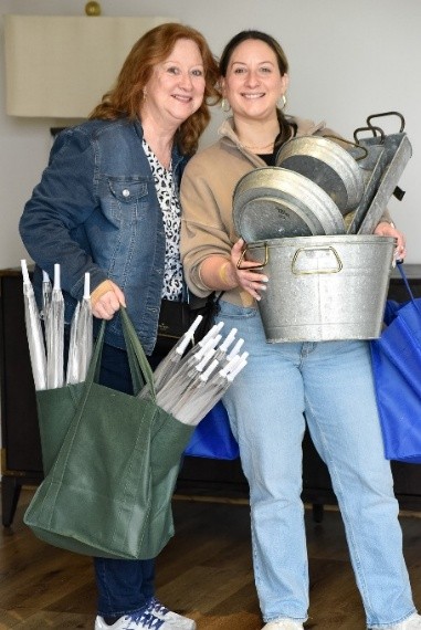 Two women holding bags and buckets of event supplies