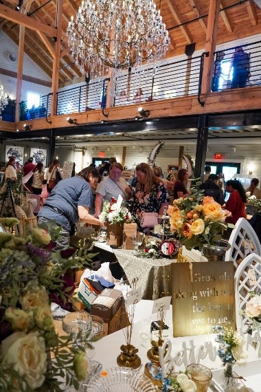 A crowded event space with tables decorated with flowers and décor