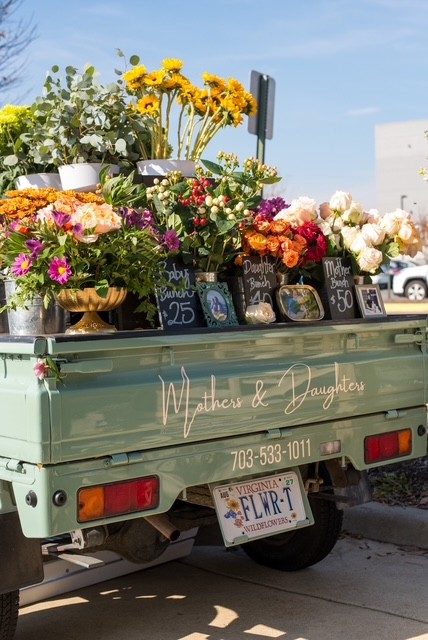 A vintage flower truck filled with bouquets at a Wedding Yard Sale event